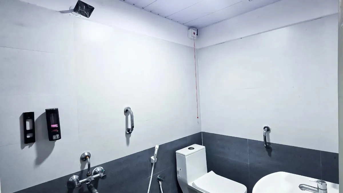 Accessible patient washroom featuring safety grab bars and an emergency pull-cord system