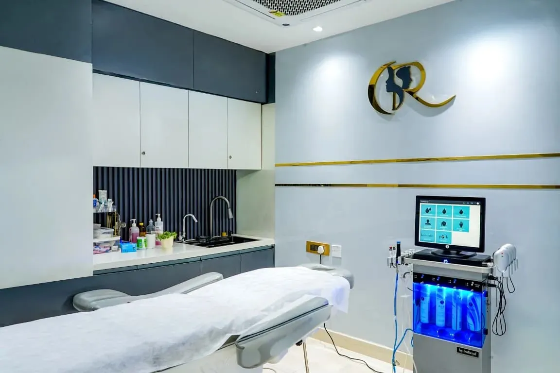 Premium skincare suite featuring the Hydrafacial Elite device and an electric examination bed