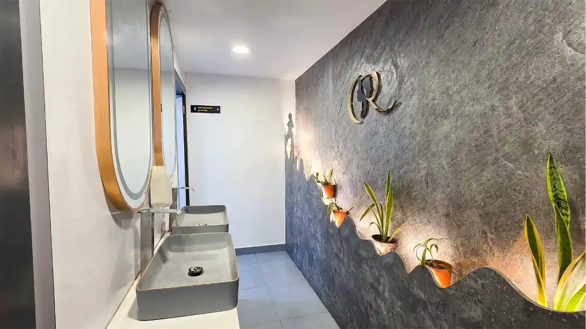 Luxury gender-neutral washroom with artistic stone cladding and touch-free sensor taps